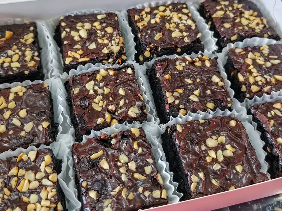 Fudgy brownies topped with chopped nuts in paper cases