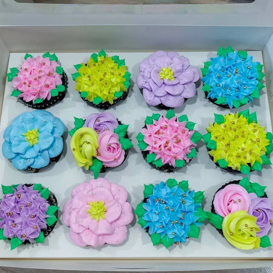 Mini cupcakes piped as colorful buttercream flowers in a white box